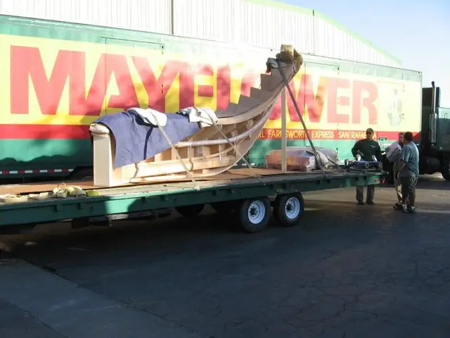 Crew loading a large framed sofa form onto a Mayflower flatbed trailer