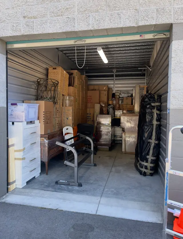 Storage room packed with labeled boxes, wrapped furniture and a bagged mattress